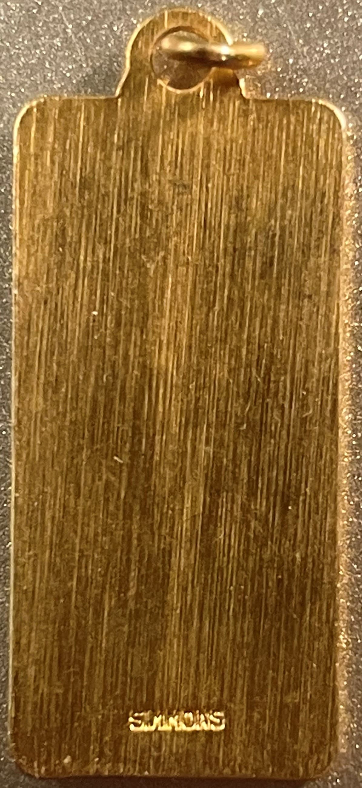 Golden rectangular pendant with brushed texture atop Vintage 1970s keychain fobs