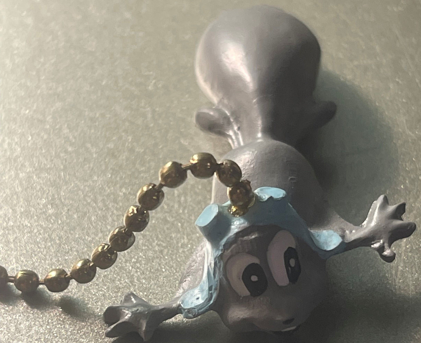 Vintage Rocky and Bullwinkle ceiling fan pull chain set with silver moose head and gold bead chain on textured surface
