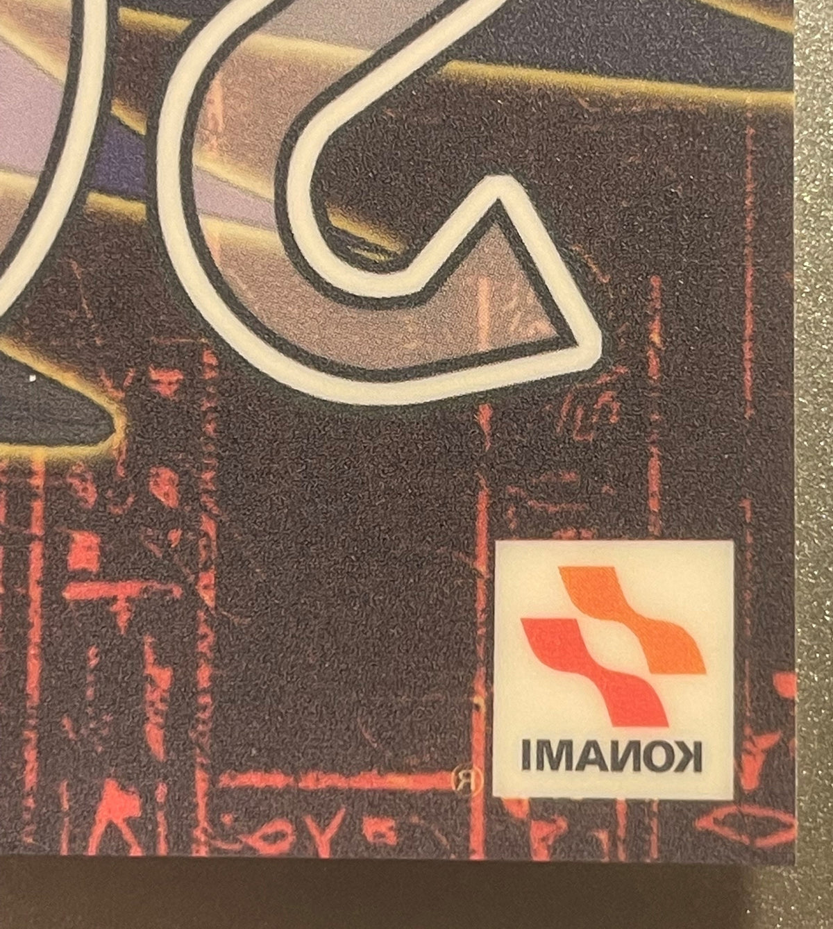 Close-up of Yu-Gi-Oh trading card game window cling showing white curved lines, red text, and Konami logo sticker on dark