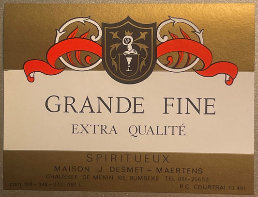Vintage wine label with ornate red ribbons and shield crest, reading "Grande Fine Extra Qualité Spiritueux" from J. Desmet-Ma