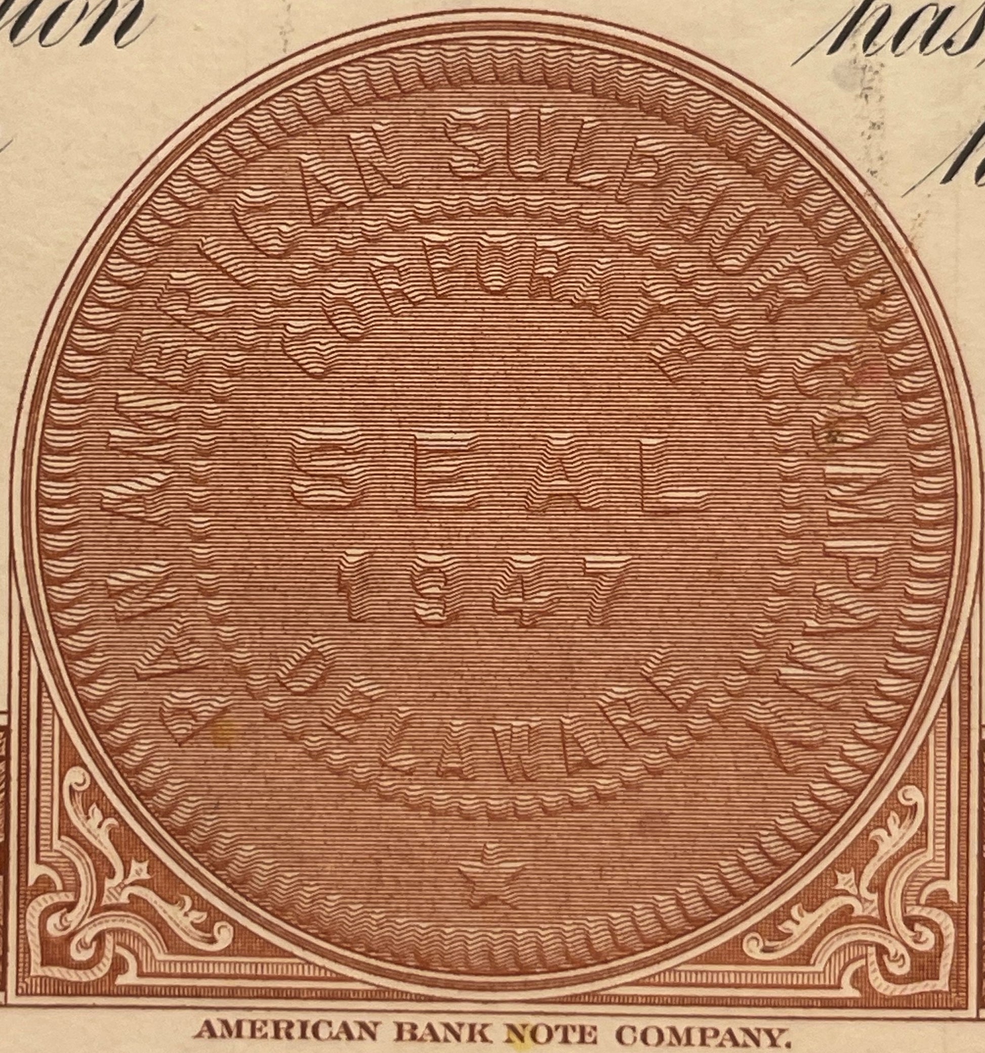 Brown engraved circular frame with wavy line fill pattern and ornamental corners, labeled "American Bank Note Company" at bot