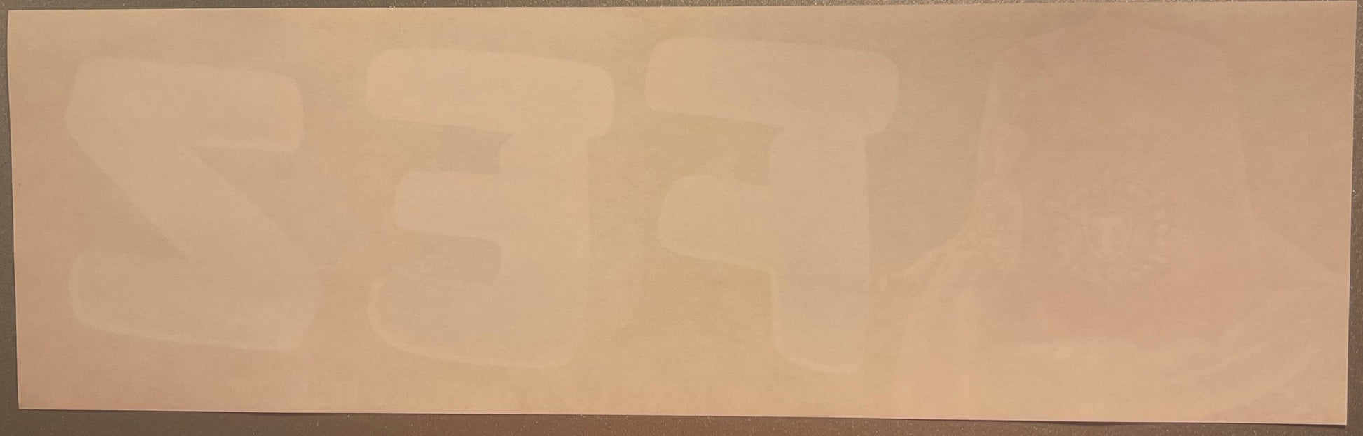 Faded vintage crate label with tan background and barely visible embossed text and decorative design, photographed flat again