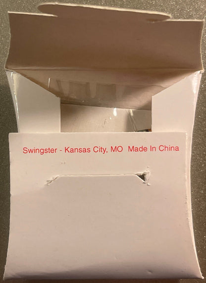 Unopened white cardboard box labeled "Swingster - Kansas City, MO Made In China" photographed from above on concrete surface