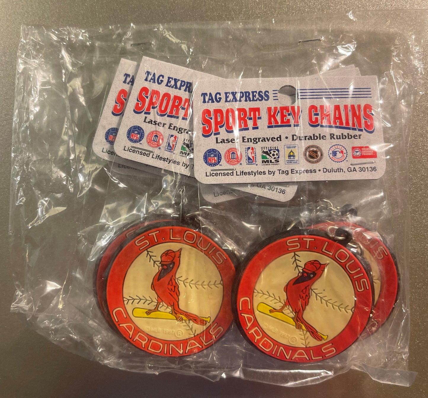 Two sealed St. Louis Cardinals rubber keychains in plastic packaging with Tag Express sport keychain labels, showing red card