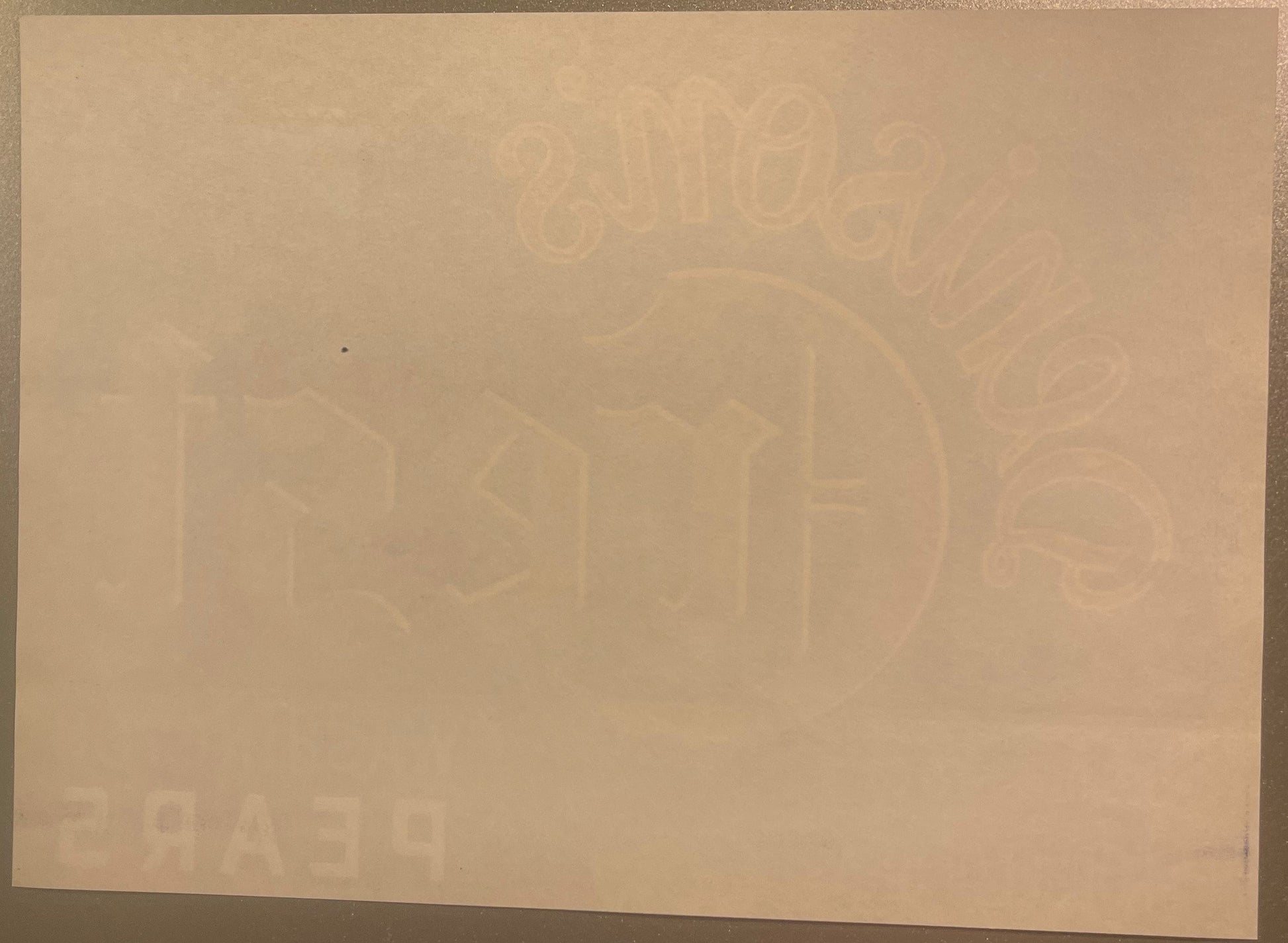 Cream-colored vintage pear crate label with faint embossed imagery of pears and decorative elements, photographed flat agains