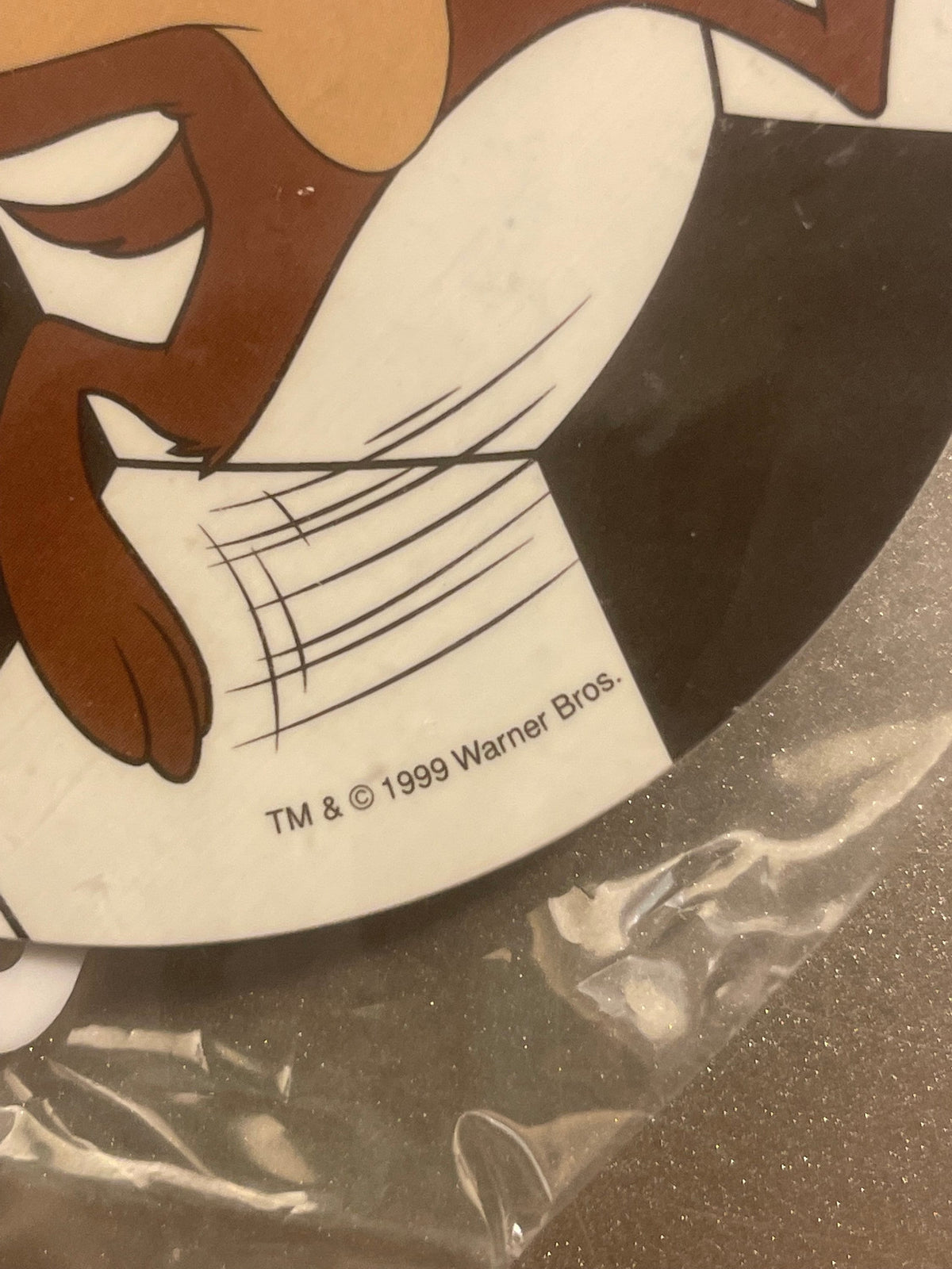 Close-up of vintage Warner Bros. cartoon character keychain showing brown character's face and cream-colored torso with cross