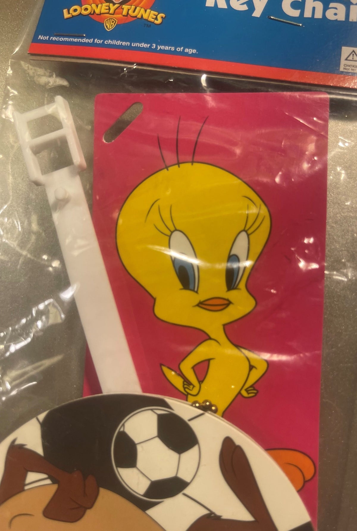 Tweety Bird keychain on pink card with white plastic attachment, soccer ball visible below, Looney Tunes branding above