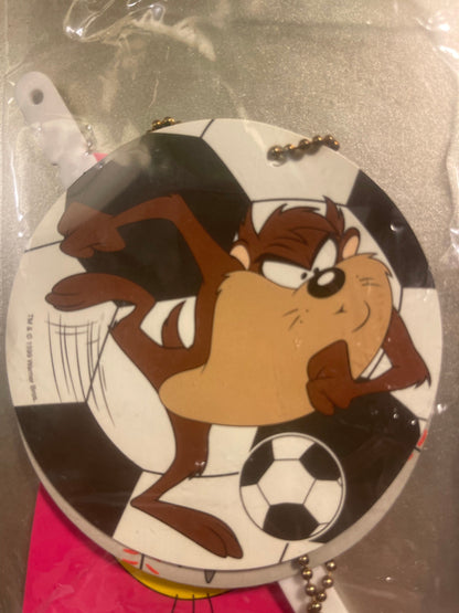 Tasmanian Devil soccer player keychain with brown fur, white shorts, black and white soccer ball, inside clear plastic