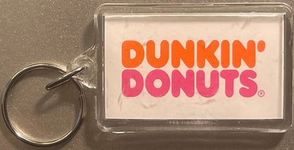 Vintage Dunkin' Donuts keychain fob with orange and pink logo on clear plastic card with metal split ring against gray backgr