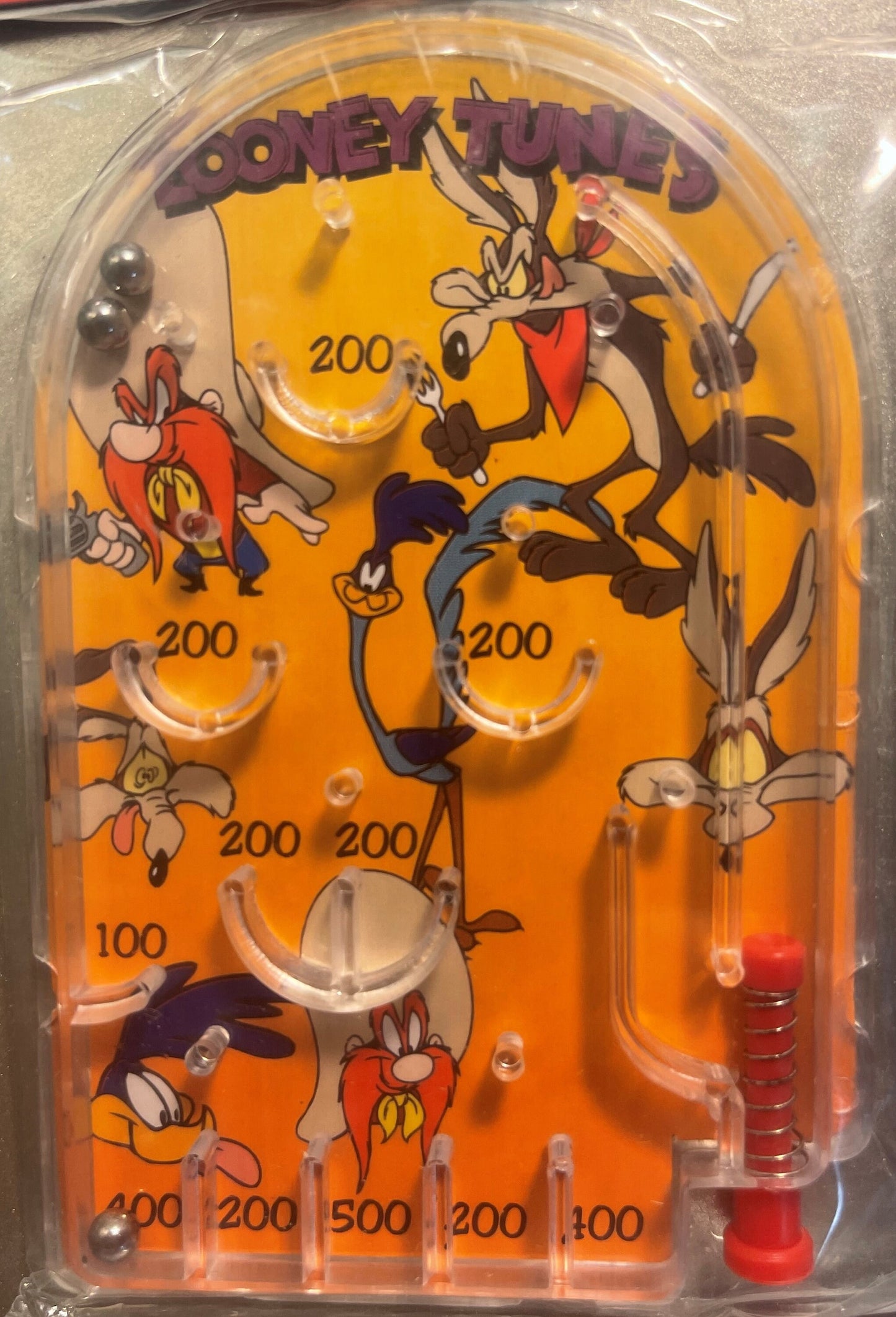 Vintage Looney Tunes mini pinball game with orange playfield featuring Wile E. Coyote and other characters, numbered scoring 