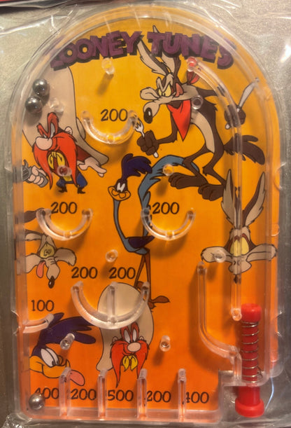 Vintage Looney Tunes mini pinball game with orange playfield featuring Wile E. Coyote and other characters, numbered scoring 