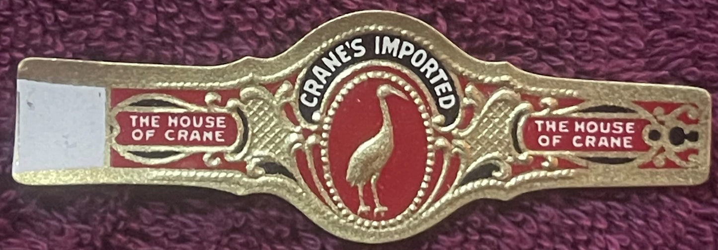 Gold-embossed cigar band with red enamel center featuring crane image, "The House of Crane" text on sides, "Cranes Imported" 