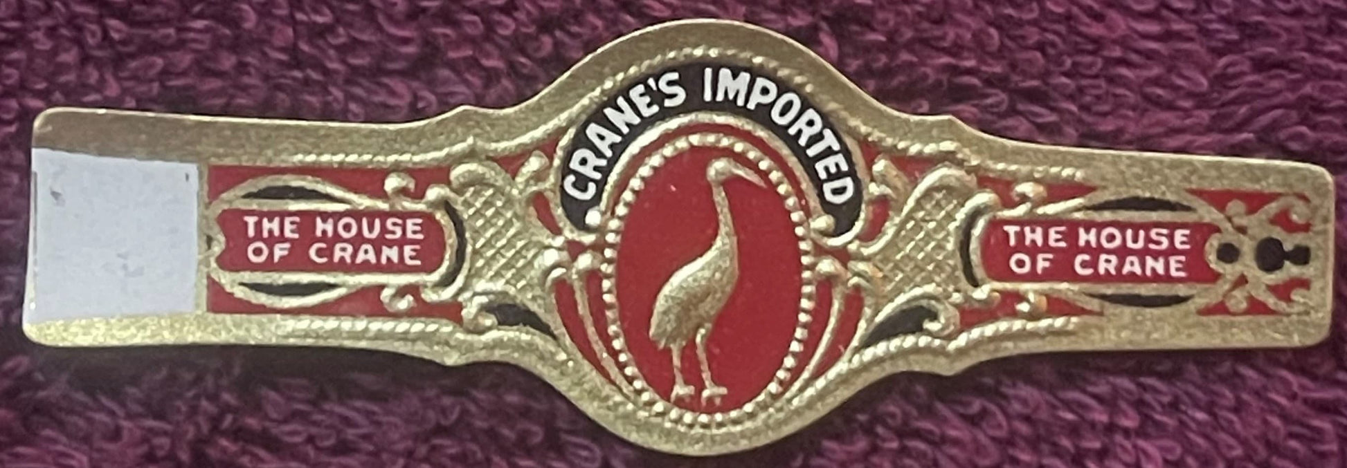 Gold-embossed cigar band with red enamel center featuring crane image, "The House of Crane" text on sides, "Cranes Imported" 