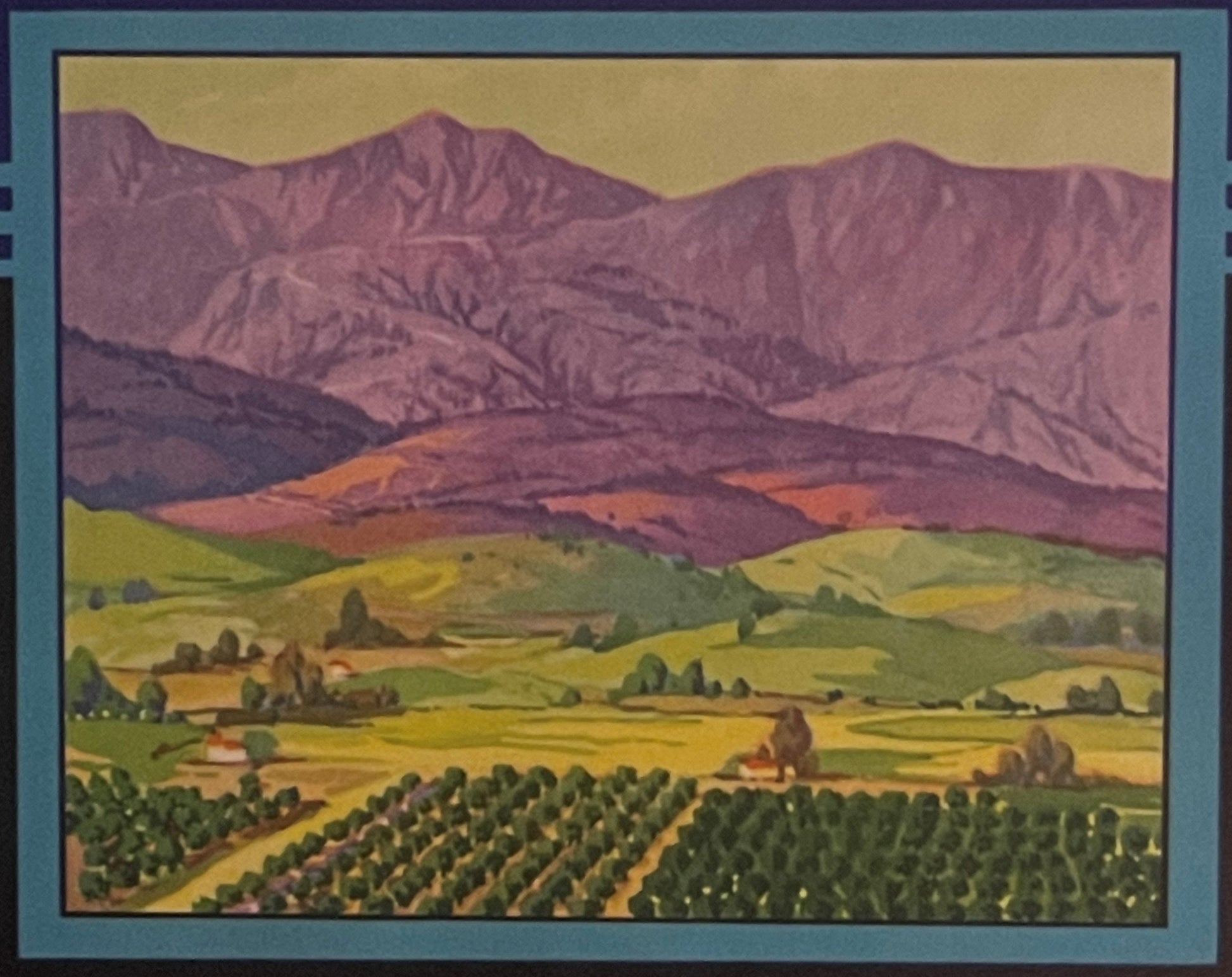Vintage lemon crate label featuring rolling green farmland with orchards below purple mountains under golden sky, framed in t