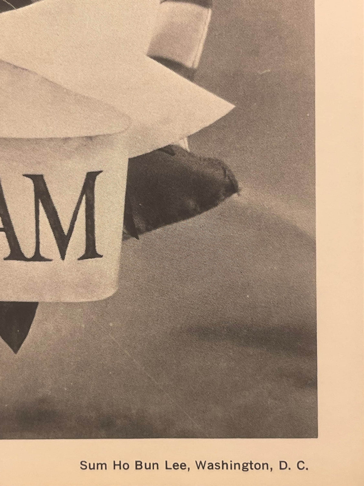 Close-up of vintage commemorative print showing "M" text and silhouette against cream and tan background, with "Sum Ho Bun Le