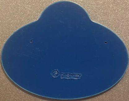 Blue Disney cast member badge with embossed logo, two mounting holes visible, photographed flat on textured surface