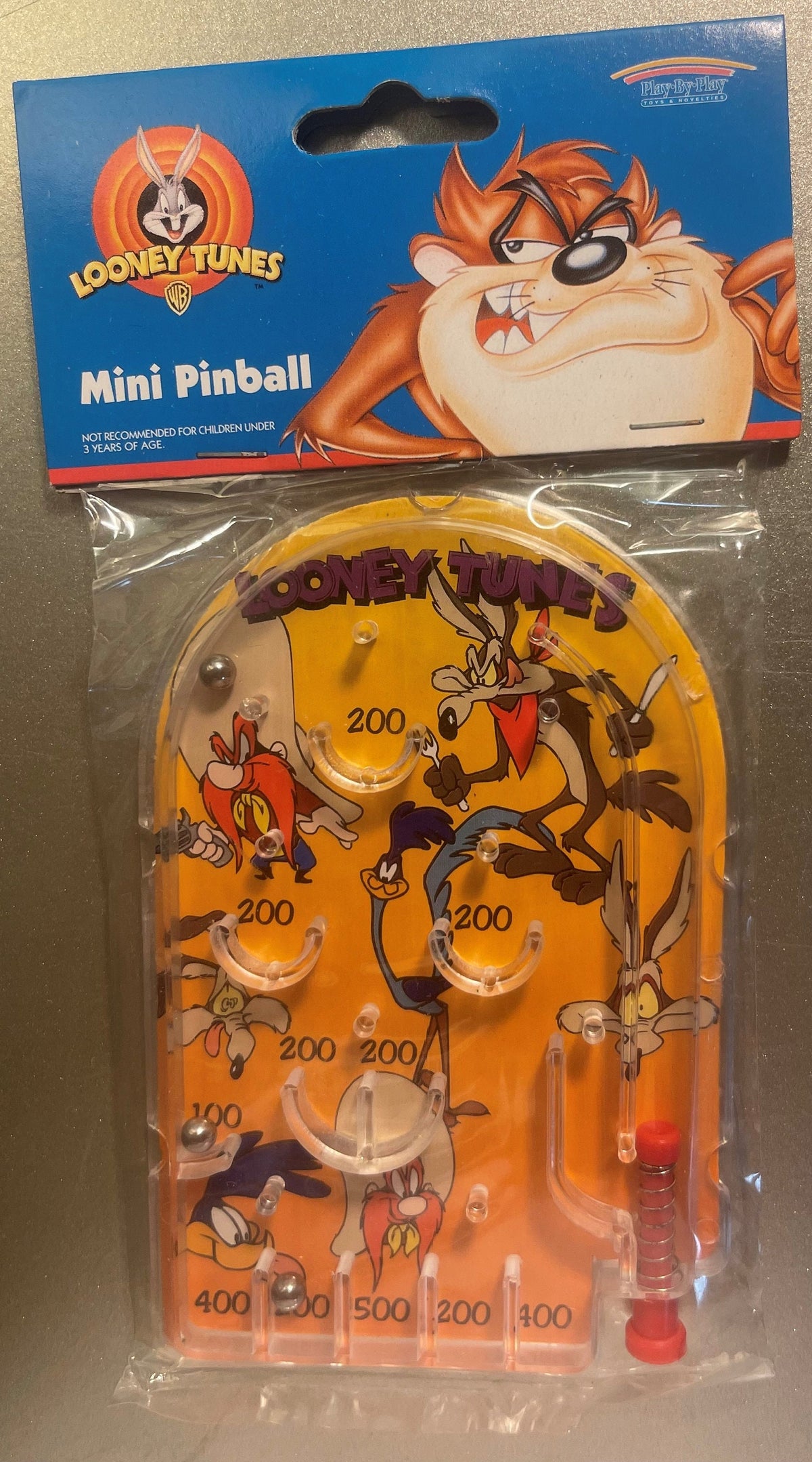 Packaged Looney Tunes mini pinball game with orange playfield featuring Wile E. Coyote and other cartoon characters, visible 