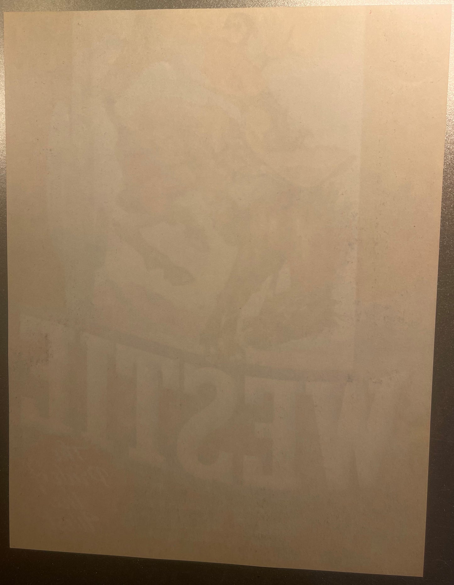 Cream-colored vintage crate label with faint printed cowboy and bucking bronco design, photographed flat against gray surface