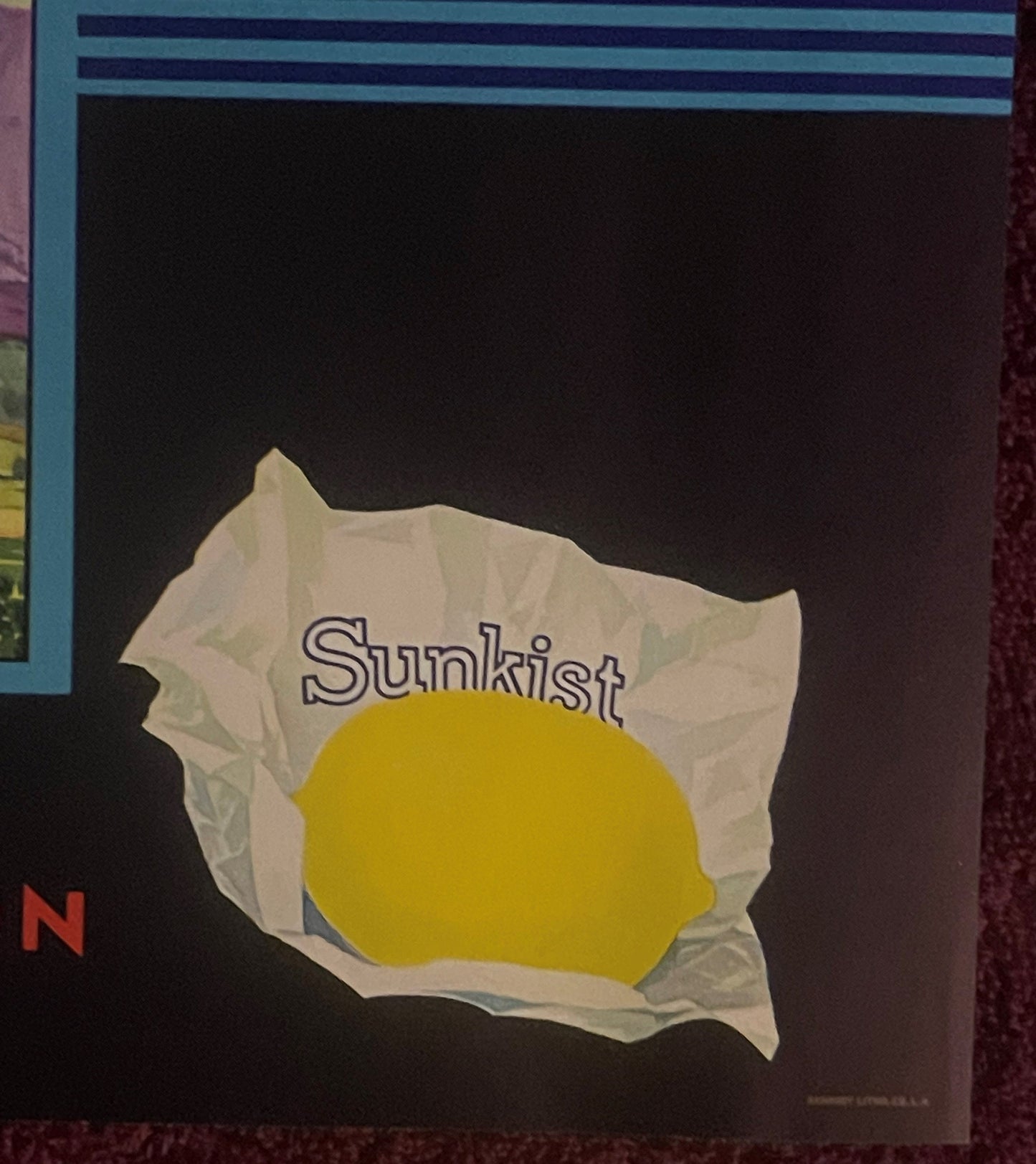 Vintage lemon crate label with "Sunkist" text on white paper wrapper around bright yellow lemon against dark background