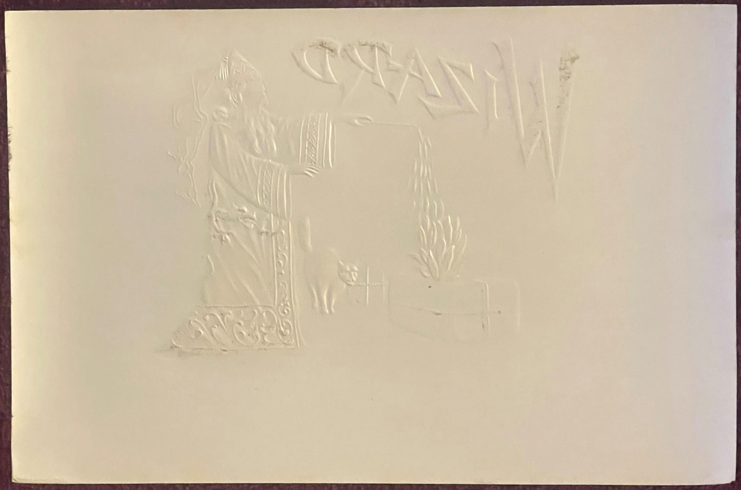 Cream-colored embossed cigar label showing a figure in robes with decorative ornamental border and text at top, photographed 