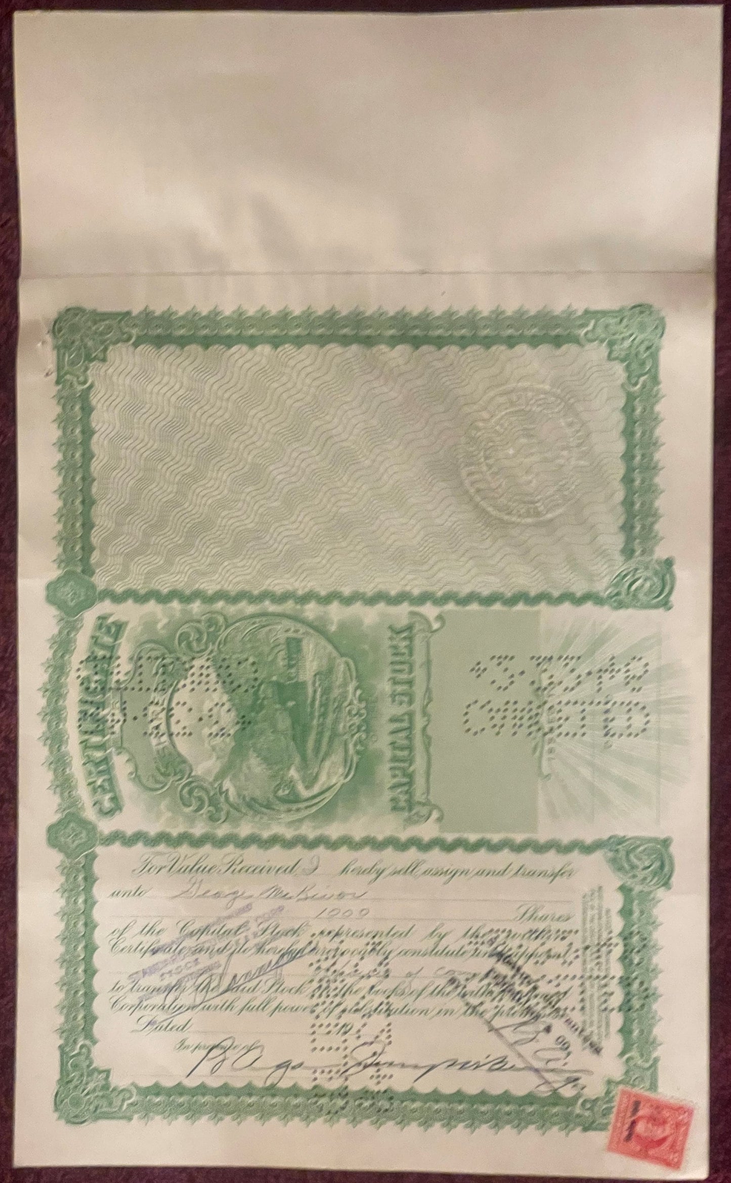 Unframed green and cream stock certificate with ornate border, decorative vignette, and handwritten signatures, small red sta