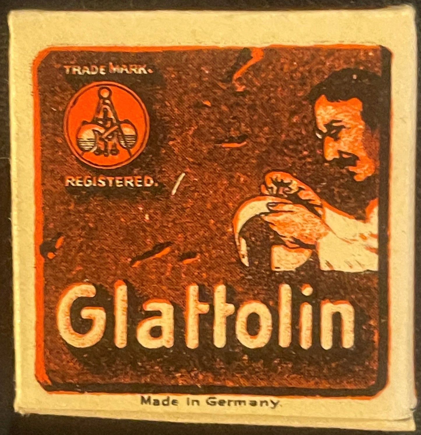 Vintage Glattolin box with orange and brown embossed design, trademark seal, and German text, displayed against cream-colored