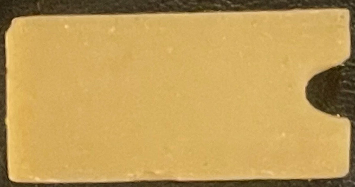 Cream-colored rectangular box with rounded right edge, shown against dark background with coin for scale