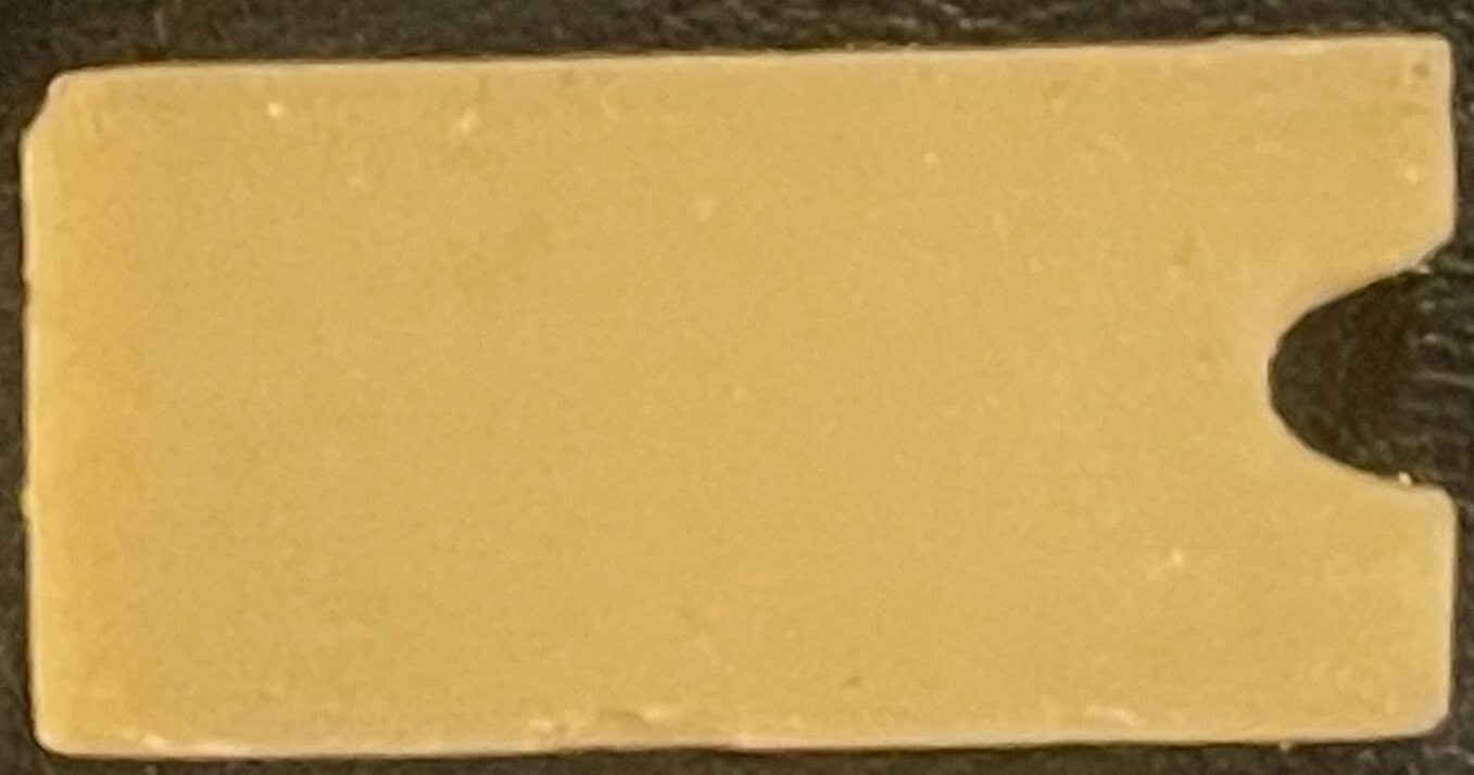 Cream-colored rectangular box with rounded right edge, shown against dark background with coin for scale
