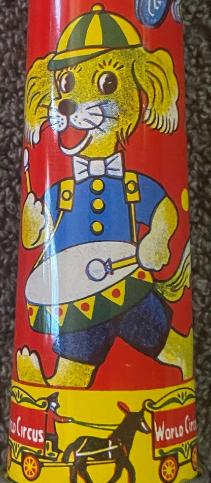 Vintage tin horn noisemaker with yellow dog character wearing striped cap, blue jacket, and bow tie against red background, c