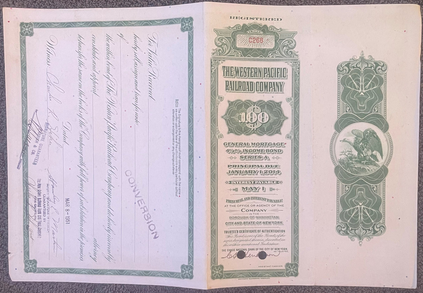 Open vintage railroad bond certificate with green ornamental borders, eagle emblem, and handwritten signatures on cream pages