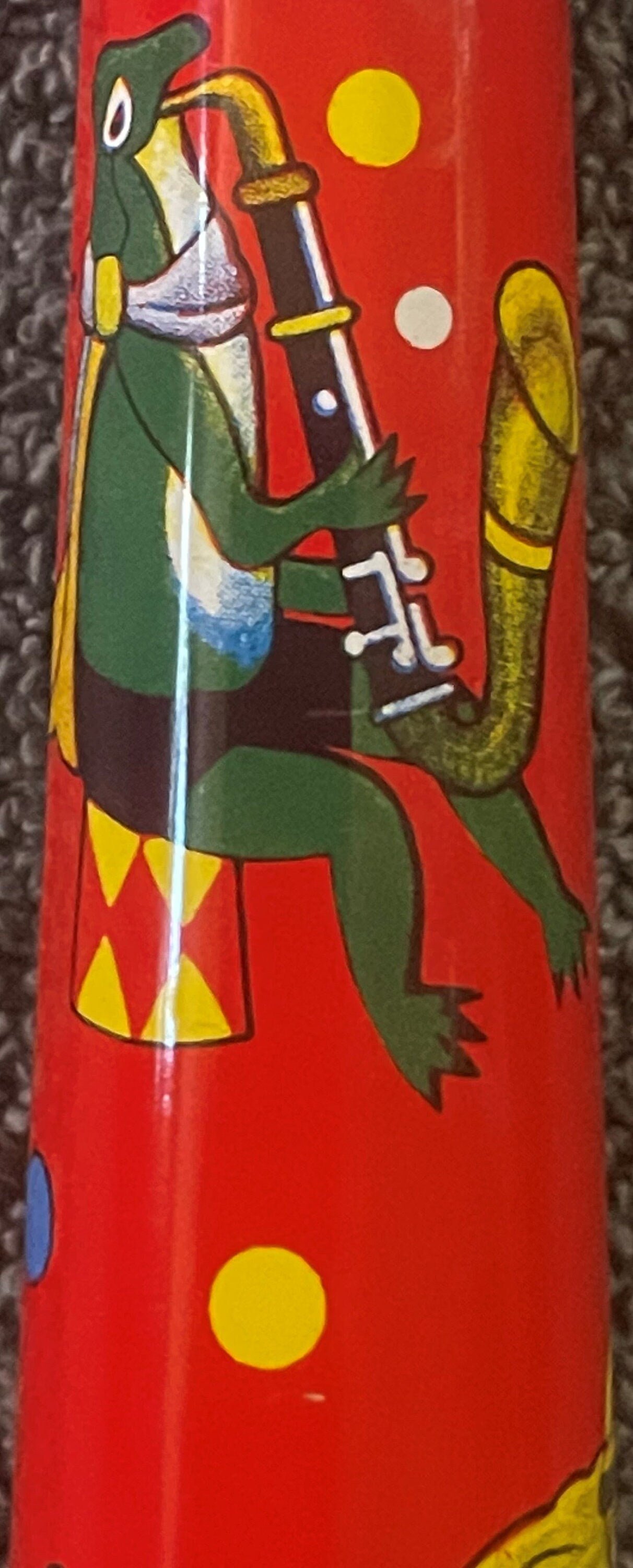 Vintage red tin horn noisemaker with colorful lithographed circus animals including green elephants and a clown figure with m