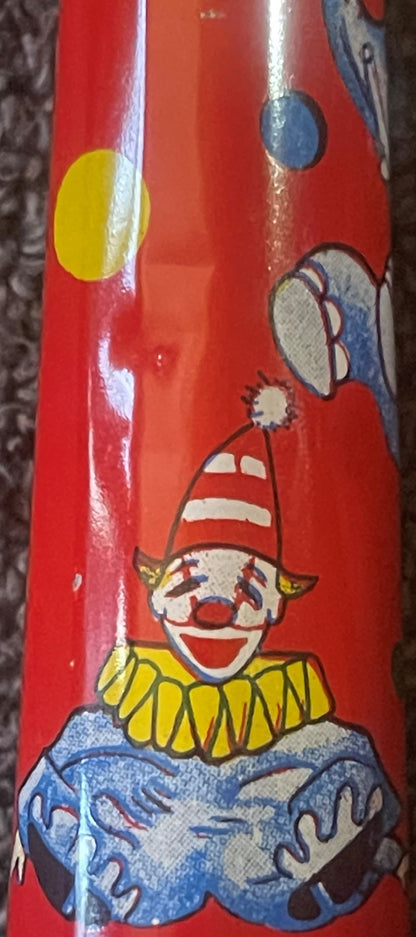 Red tin horn noisemaker featuring a smiling clown with yellow ruffled collar, red cone hat, and blue clothing, with juggling 