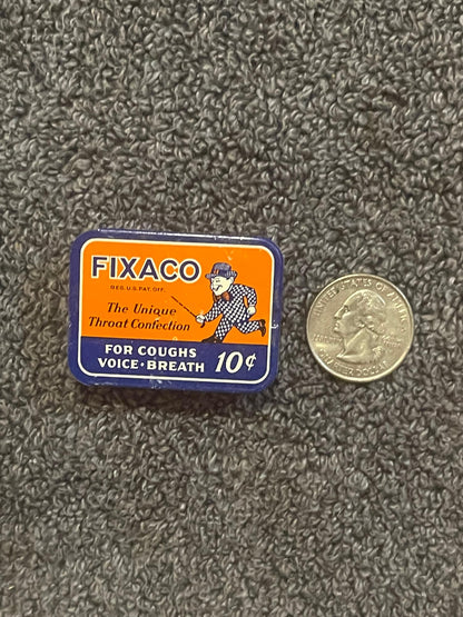 A FIXACO tin photographed beside a US quarter for scale, the coin about as wide as the tin is deep.