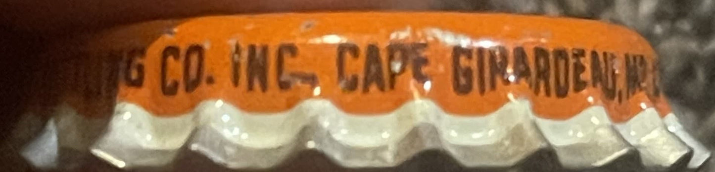 Close-up of orange and white cork bottle cap with embossed text reading "G CO. INC. CAPE GIRARDEAU MO