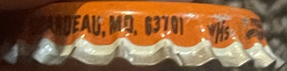 Close-up of orange and white ridged cork bottle cap with embossed text, shown at an angle
