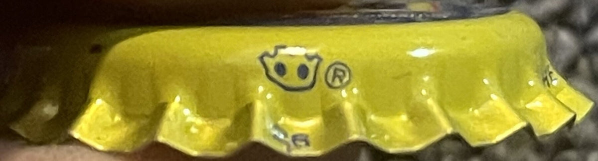 Vintage yellow bottle cap with embossed smiley face logo and registered trademark symbol, shown in close-up detail