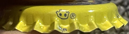 Vintage yellow bottle cap with embossed smiley face logo and registered trademark symbol, shown in close-up detail