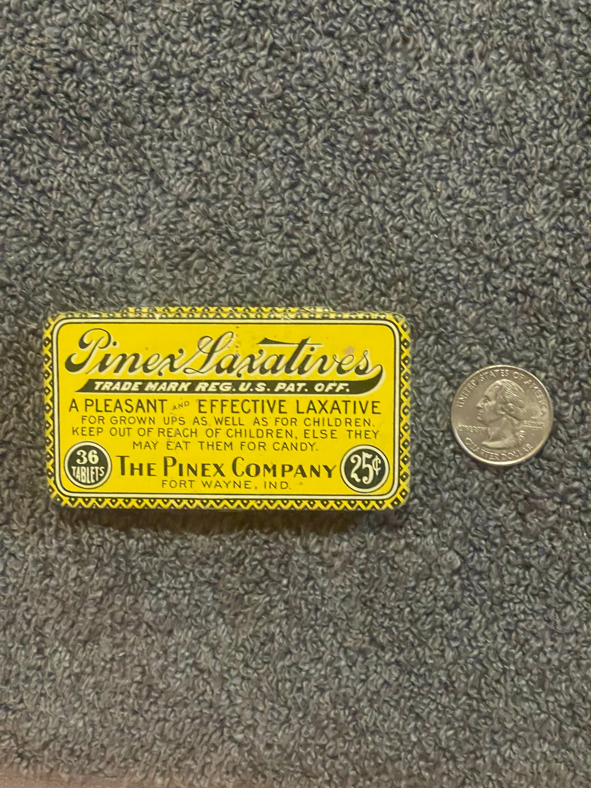 Vintage yellow Pinex Laxatives tin from Fort Wayne, Indiana, displayed next to a quarter for scale