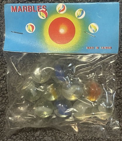 Unopened package of marbles with blue box showing red sphere surrounded by yellow glow and smaller marbles, marked "Made in T