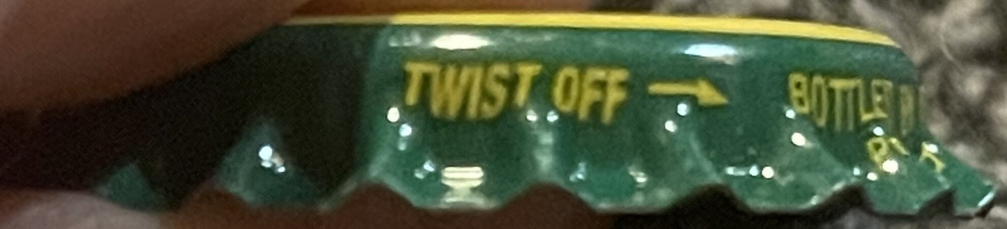Vintage green and gold twist-off bottle cap with "TWIST OFF" and "BOTTLE" text visible, shown at an angle against a textured 