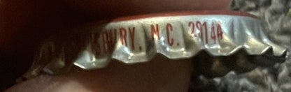Close-up of vintage bottle cap showing red and white ridged metal with partial text reading "ARRY", "N.C." and "291 14