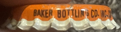 Vintage cork bottle cap with orange top and white ridged cork base, printed "BAKER BOTTLING CO. INC." in dark text, shown in 