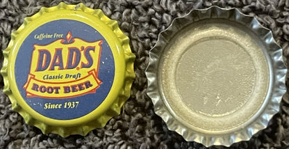 Vintage Dad's Classic Draft Root Beer bottle cap from Chicago IL, shown front and back on textured fabric, yellow crown with 