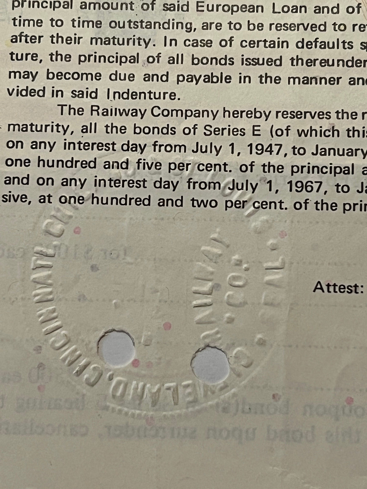 Close-up of embossed railroad bond document showing text about Series E bonds and interest rates, with two circular holes pun