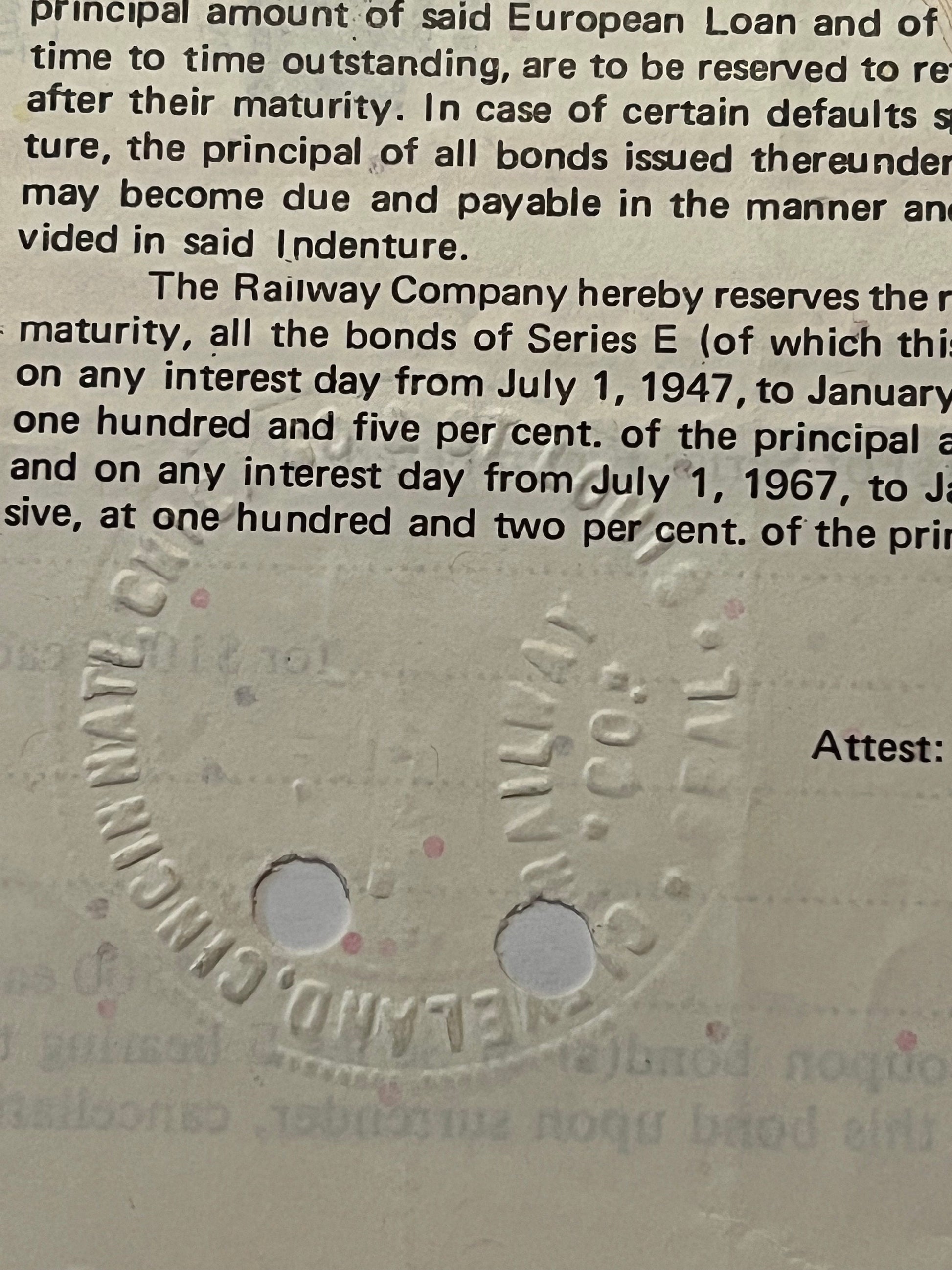 Close-up of embossed railroad bond document showing text about Series E bonds and interest rates, with two circular holes pun