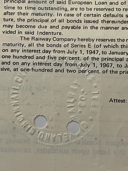 Close-up of embossed railroad bond document showing text about Series E bonds and interest rates, with two circular holes pun