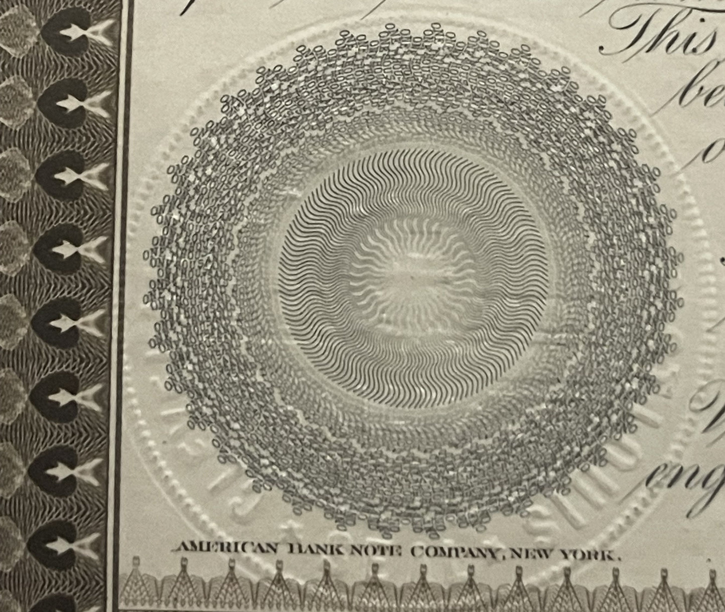 Close-up of ornate circular engraving with concentric wavy lines on antique bond certificate, showing "American Bank Note Com