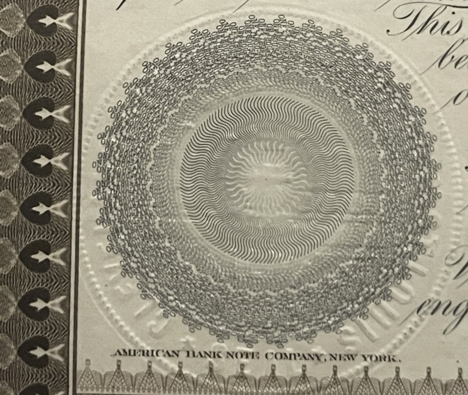 Close-up of ornate circular engraving with concentric wavy lines on antique bond certificate, showing "American Bank Note Com