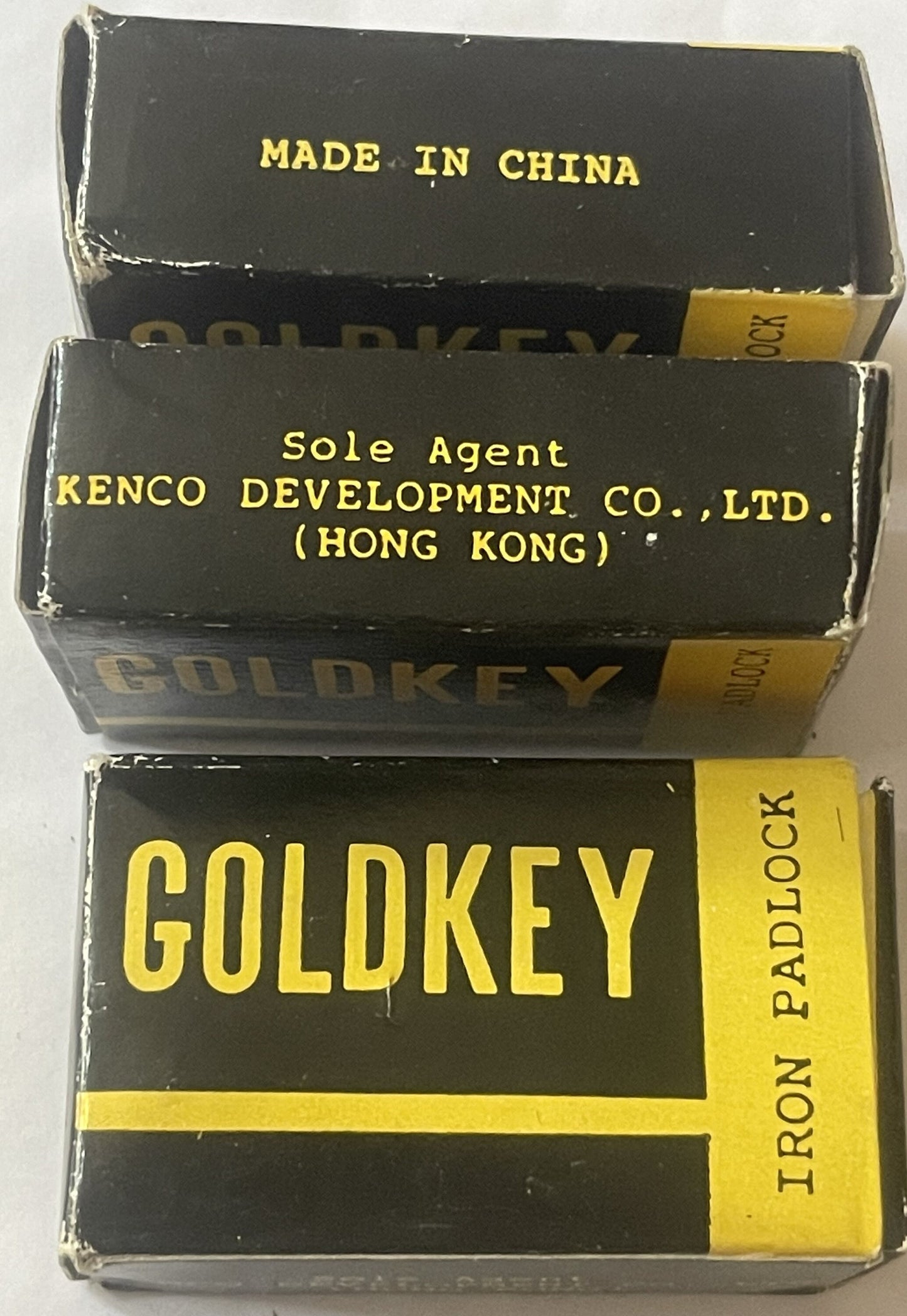 Three stacked vintage GoldKey iron padlock boxes with black and yellow labeling, made in China, sole agent Kenco Development 