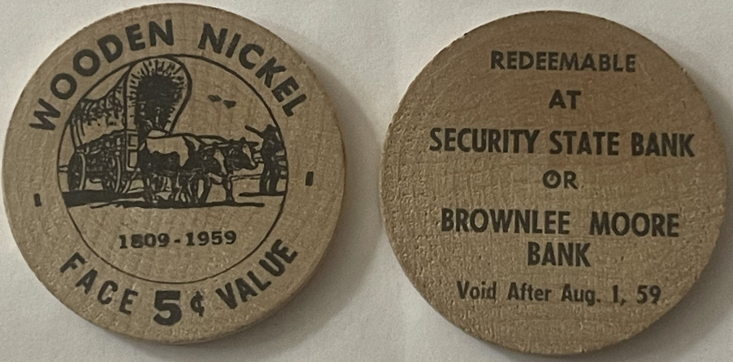 Front and back of wooden quarter coin showing covered wagon scene dated 1909-1959, face value 5¢, redeemable at Security State